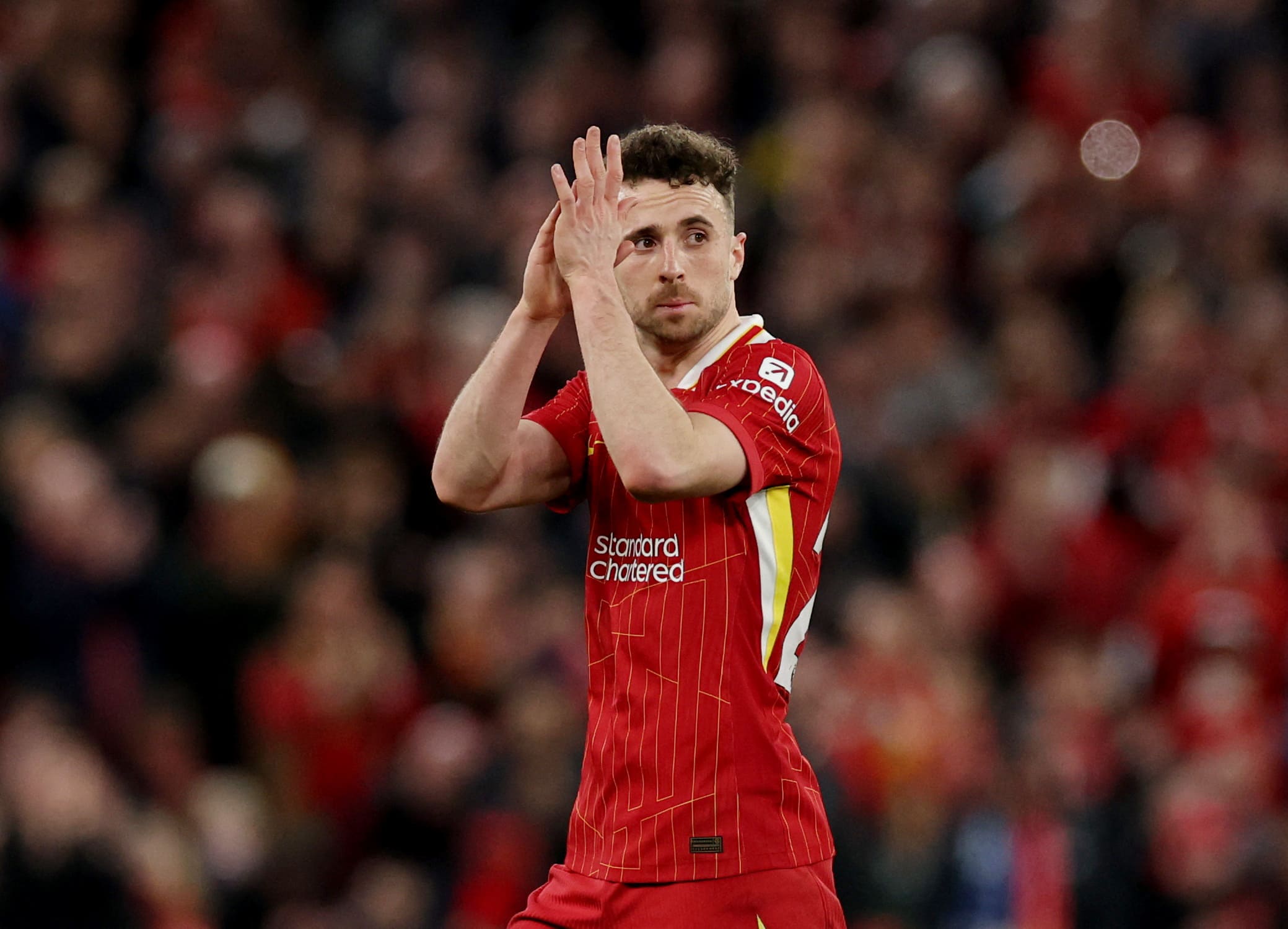 Diogo Jota in action on the football pitch, wearing a Liverpool jersey, focused and sprinting with the ball during a competitive match.