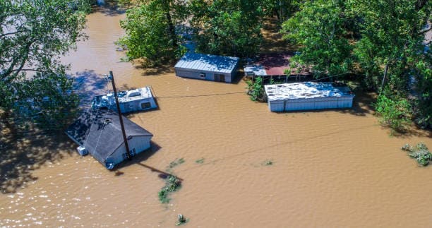 The swollen riverbanks of Texas overflow after torrential rains, submerging nearby roads and communities under dangerous floodwaters.