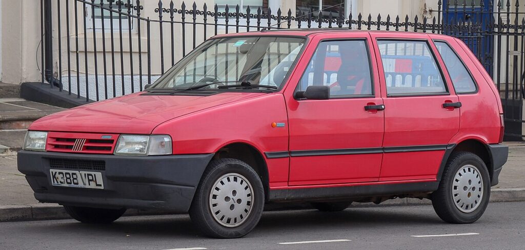 Red Fiat Uno parked on a Nepali street, showing its exterior design.
