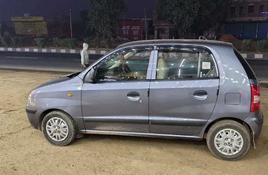 Silver Hyundai Santro Xing parked on a road in Nepal with buildings in the background.