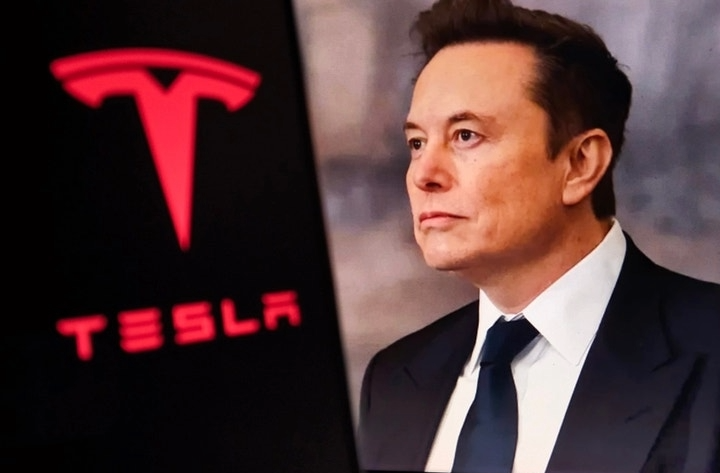 A man in a business suit stands beside the Tesla logo in a corporate-style image related to reporting on large stock-based compensation awarded to Tesla’s board.
