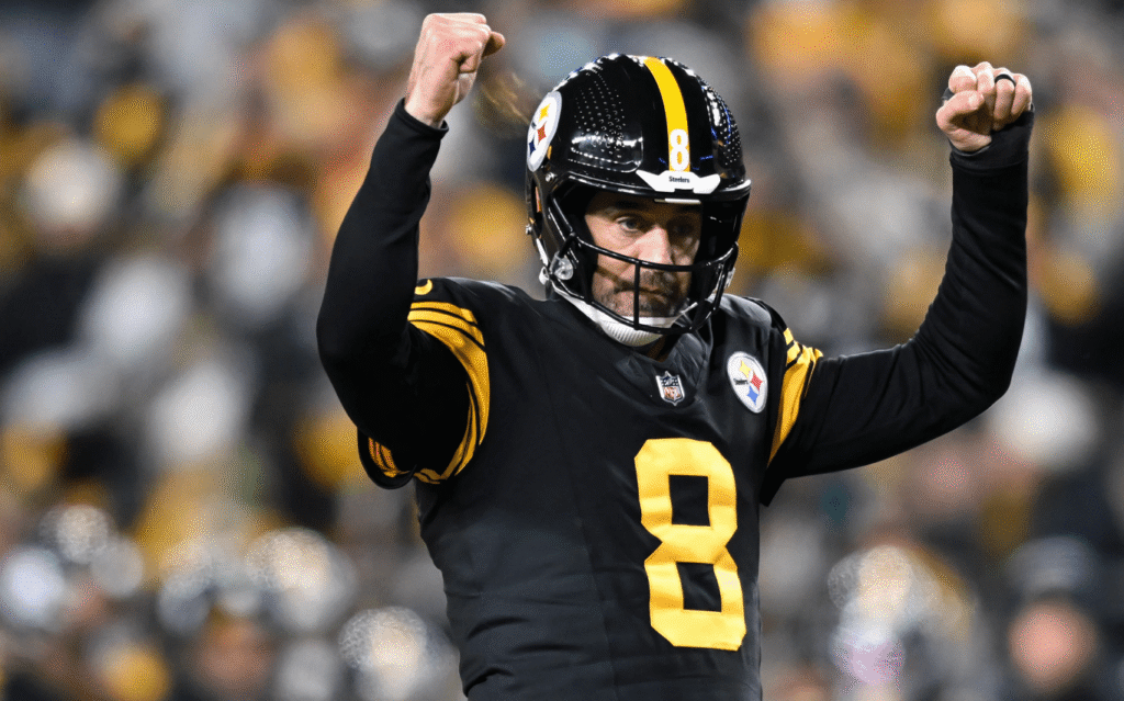 A Pittsburgh Steelers player wearing a black and gold uniform raises both fists in celebration during a Monday Night Football game against the Miami Dolphins.