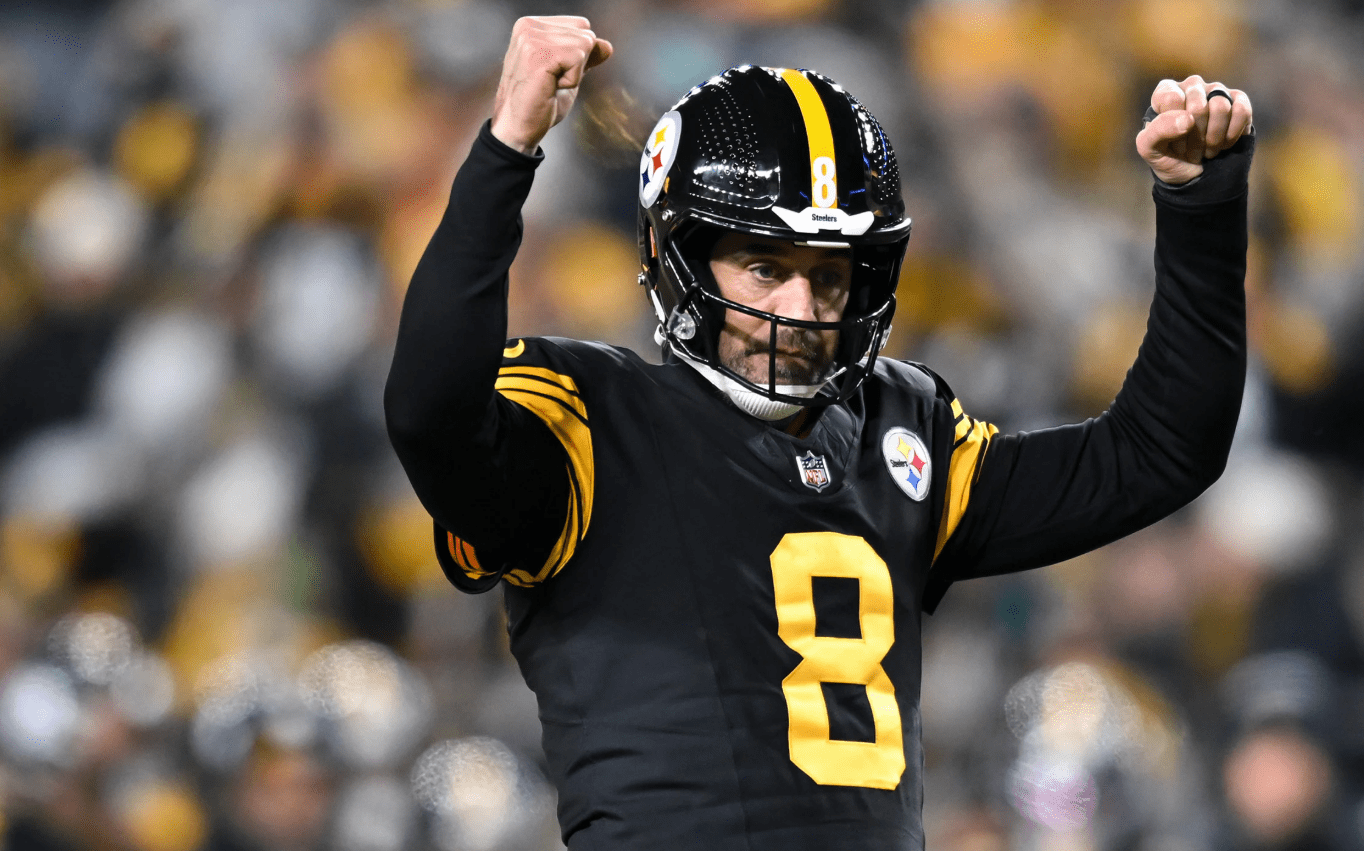 A Pittsburgh Steelers player wearing a black and gold uniform raises both fists in celebration during a Monday Night Football game against the Miami Dolphins.