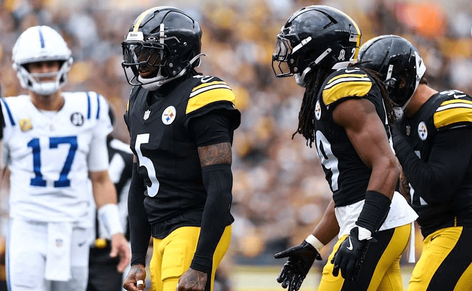 Pittsburgh Steelers quarterback in a black and gold uniform raises both arms in celebration during a Monday Night Football game against the Miami Dolphins.